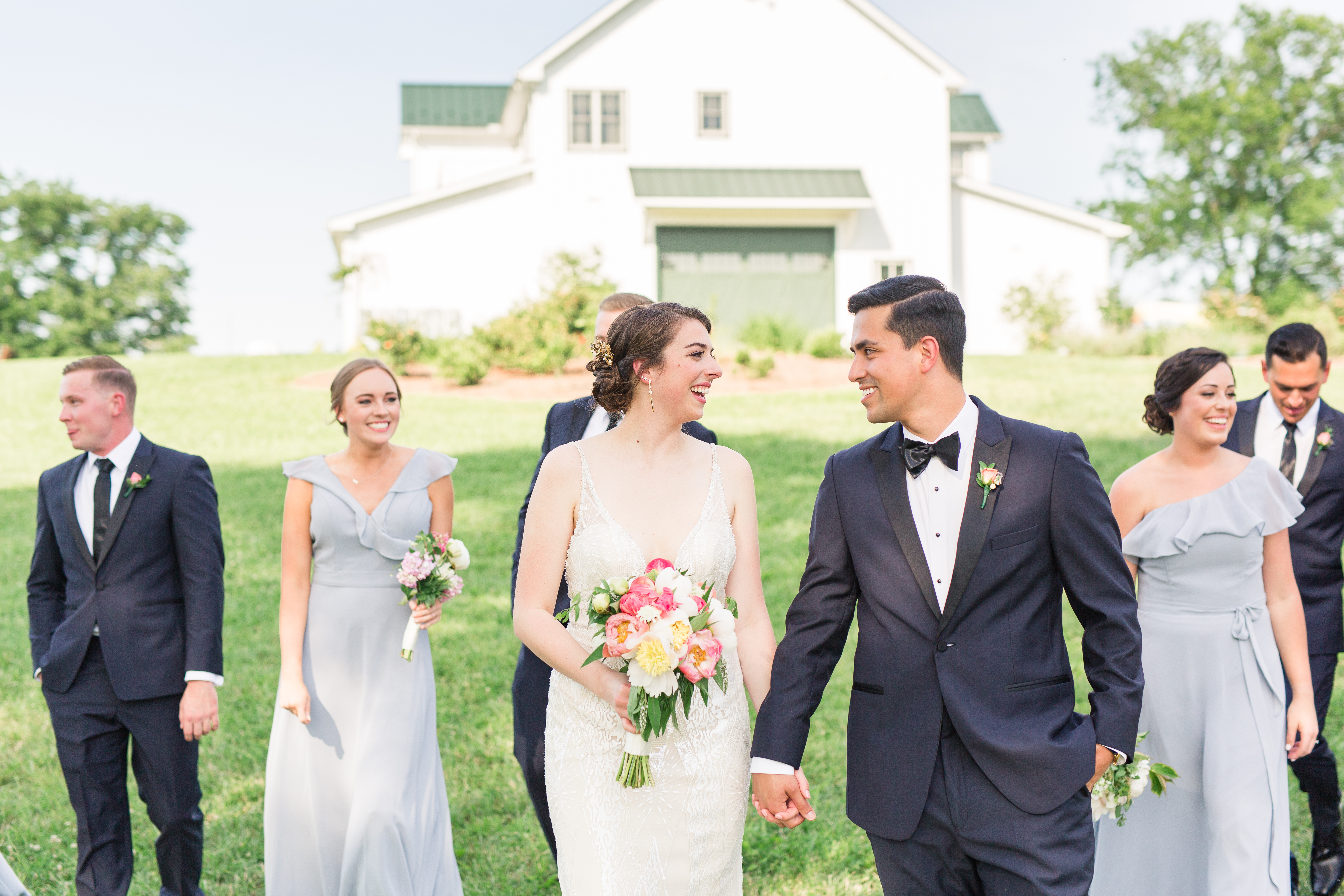 Bride and Groom walking with bridal party in front of barn venue