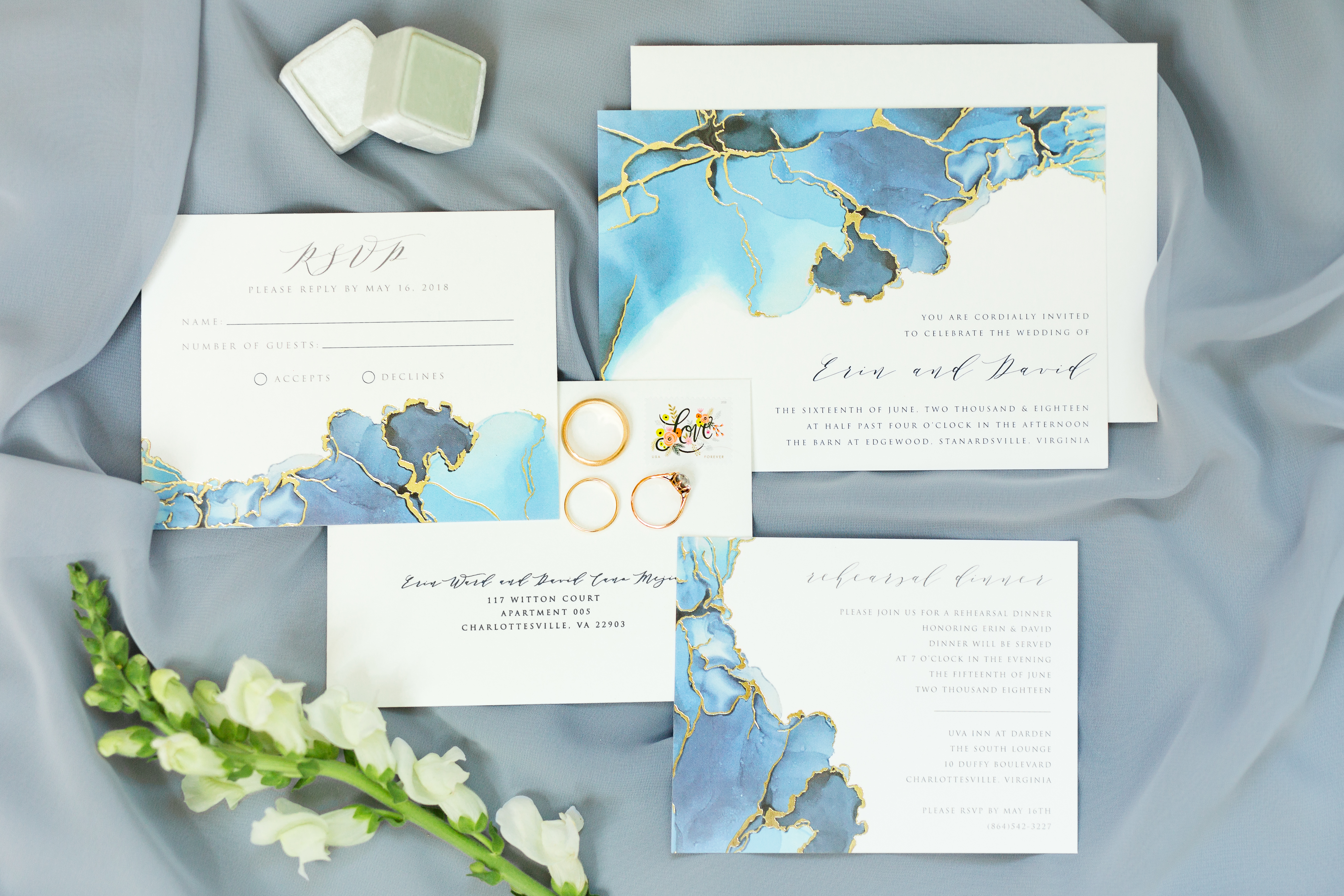 Blue, Green and Gold foiled invitation suite with a mrs box and an engagement ring against a grayish blue bridesmaid dress