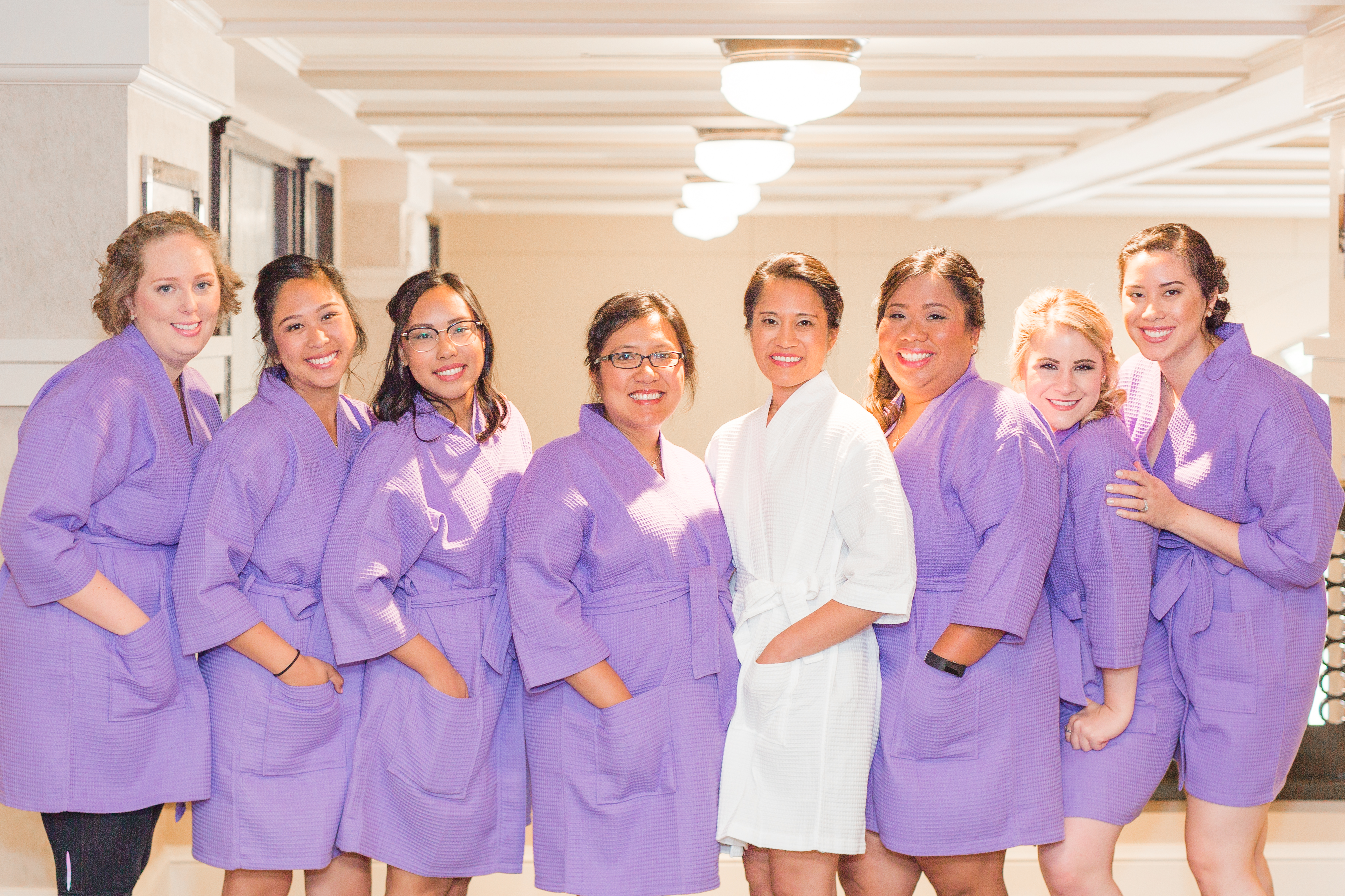 the bride and her bridesmaids in their purple getting ready robes